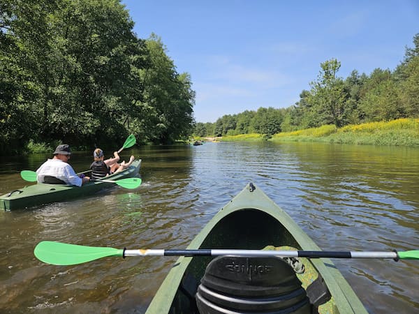 Widok z kajaka na rzekę Tanew w tle inny kajak z kajakarzami